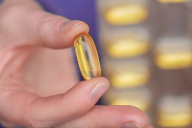 Omega yağ asitleri. Eldeki balık yağı kapsülleri. Sağlıklı yağ ve kadınlar için. Kadın beslenme malzemeleri ve vitaminler. 