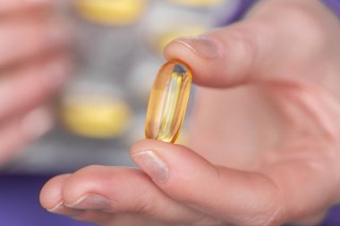 Kadın ellerinde balık yağı kapsülleri. Omega yağ asitleri jöle kapsülleri. Sağlıklı yağlar ve kadınlar. Kadınlarda beslenme takviyeleri ve vitaminler. Kadın sağlığı için balık yağı.
