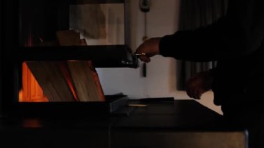 Ev şöminesi. Adam karanlık bir odada yanan bir şömineyi kapatıyor. Sıcak atmosfer. Şöminede yangın. İçeride şömine var. 4k görüntü