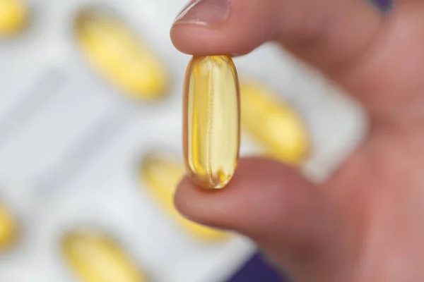 Fish oil for womens health. Fish oil capsules in female hand.Omega fatty acids jelly capsules.Healthy fats and womens health.Dietary supplements and vitamins in womens nutrition.