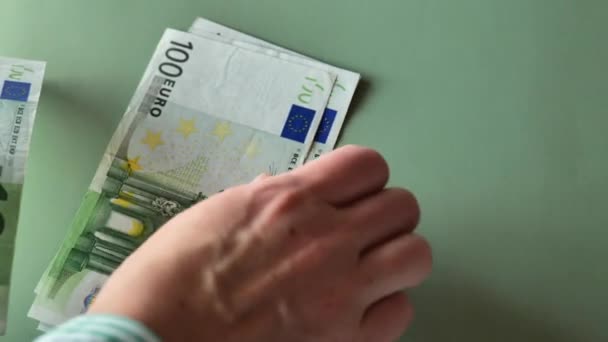 ユーロ紙幣を数える手 スローモーション 緑の背景にストライプのシャツを手にユーロのお金 100ユーロの請求書のパック ヨーロッパ連合のお金 収入と支出 — ストック動画