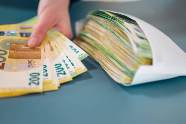 Zarfta para var. Zarftaki maaş... paranın yeniden hesaplanması. Avro banknotları, Avrupa ülkelerindeki gri zemin harcamaları ve gelirleri içeren bir zarfın içinde. Para ve finans. 