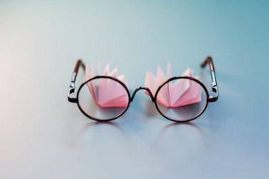 Eğitim ve öğrenim. Okuma ve Edebiyat. Mavi arka planda bir kitabın sayfaları ve dekoratif kitapların üzerine yakın plan okuma gözlüğü. Eğitim, bilgi ve okuma sembolü. Eğitim sembolü.