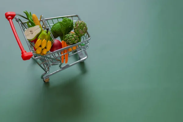 Food grocery basket.food basket cost.Rising food prices.Shopping cart with groceries on green background.Vegetables and fruits price.Decorative supermarket trolley with groceries.Food prices.