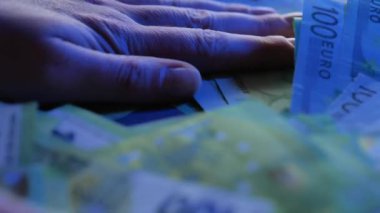 Avro parası. Eller mavi ışıkta masanın üzerindeki avro banknotlarını tırmıklıyor. Nakit ödendi. 4k görüntü