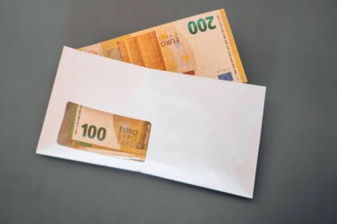 Zarfın içinde para. Avro faturaları, zarflarda maaş. Avro banknotları, gri bir arkaplanda bir zarfın içinde. Avrupa ülkelerindeki giderler ve gelirler.