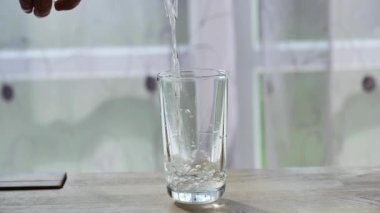 Su şeffaf bir bardağa dökülür. Su jeti ağır çekimde. İçme modu. 4k görüntü