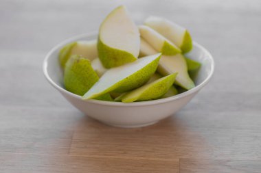 Dilimlenmiş inci. Parlak bir mutfakta, ahşap bir masada yeşil bir armut dilimliyorum. Meyve kesimi. Sağlıklı meyve atıştırmalığı. Diyetteki taze meyveler