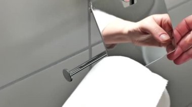 Tuvalet kağıdı. Banyo malzemeleri. Eller tuvalet kağıdını bir tutacağa koyuyor. Temizlik ve sağlık konsepti. 4k görüntü