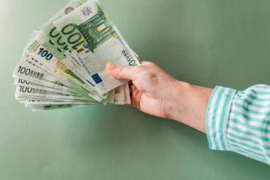 Avro Bölgesi 'ndeki bir kadının yeşil zemin üzerinde çalışan 100 avroluk banknotlar. Avrupa ülkelerindeki kadınların geliri.