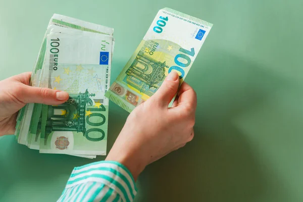salary of a woman in the Eurozone. euro banknotes in female hands on a green background. Income of women in European countries.Earnings and spending in the Eurozone