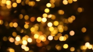 Koyu arkaplandaki altın bokeh. Noel ağacı arka planında parıldayan çelenkler. Güzel bir Noel arkaplanı. 4k görüntü