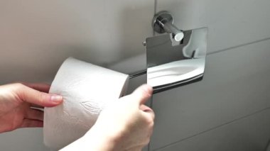 Tuvalet kağıdı rulosu. Eller bir rulo tuvalet kağıdını tutacağa koyuyor. Hijyen ve temizlik malzemeleri. 4k görüntü