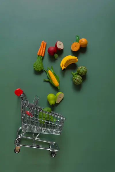 Shopping food background. supermarket trolley with vegetables and fruits on a green background.Rising food prices.Vegetables and fruits price increase.Shopping cart with groceries