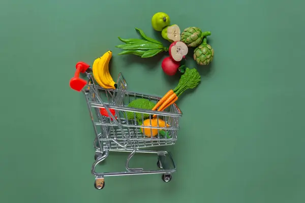 Vegetables and fruits price .Shopping cart with groceries. Shopping food background. supermarket trolley with decorative vegetables and fruits on a green background.