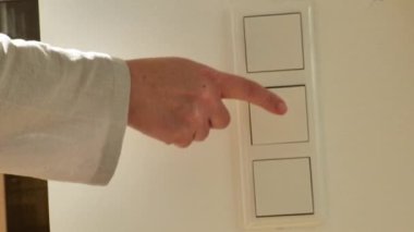 Üç düğmeli elektrik düğmesi. Enerji tasarrufu. Makul elektrik tüketimi. Kadınların eli, odadaki ışığı yakın çekimde söndürür. Enerji ve elektrik. Işıklandırma ekipmanı