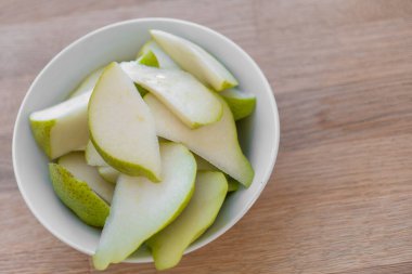 Parlak bir mutfakta, ahşap bir masada armut dilimlenmiş. Meyve kesimi. Sağlıklı meyve atıştırmalığı. Diyetteki taze meyveler