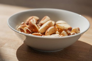 Brezilya fındığı beyaz seramik bir fincanda, tahta bir masanın üzerinde, sağlıklı şişmanlar, diyette Brezilya fındıkları, fındıklar ve tohumlar. Faydalı sağlıklı atıştırmalık.