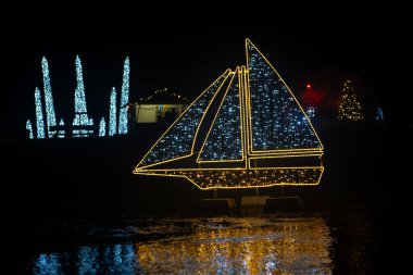 Parlak çelenklerden yapılmış bir Noel gemisi. Gece caddelerinde parıldayan sokak manzarası. Çiçeklerin Noel süsleri..