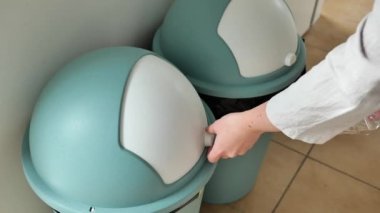 Çöp ayıklama. Plastik atık. Kadın eli, gri kullanılmış çöp kutusuna plastik çöp atar. Sıfır atık. 4k görüntü