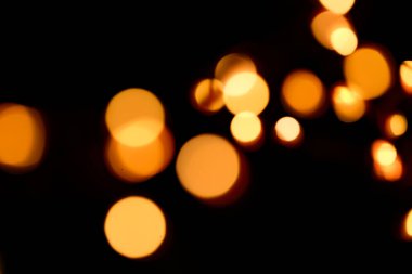 Duvar kağıdı bokeh. Parlak kumaş. Siyah arka planda sarı boke. Yılbaşı ve Noel Festivali geçmişi. Sıcak Bokeh festivali geçmişi..