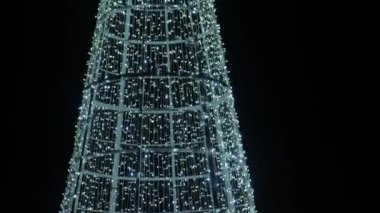 Noel tesisleri. Karanlıkta ışıl ışıl çelenkler kulesi. Parlak dekoratif tatil eşyaları. 4k görüntü