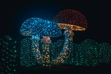 Rengarenk çelenklerden parlayan mantarlar. Noel süsleri. Karanlıktaki çelenklerden parlayan Noel figürleri. Çelenklerle kurulmuş..