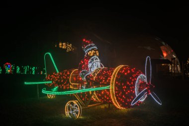Parlayan çelenklerin Noel 'de kurulması. Noel Baba helikopterde parlayan bir tesiste. Karanlıktaki çelenklerden yapılmış Noel sokak dekoru. Parlayan Noel figürleri.