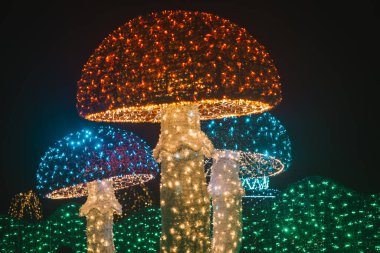 Noel süslemeleri sokak dekorasyonu. Çok renkli çelenklerden parlayan dev mantarlar. Karanlıkta parlayan Noel figürleri..