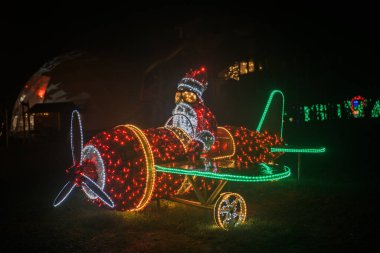 Parlayan çelenklerin Noel sokağı kurulumu. Noel Baba helikopterde. Karanlıktaki çelenklerden yapılmış Noel sokak dekoru. Parlayan Noel figürleri.