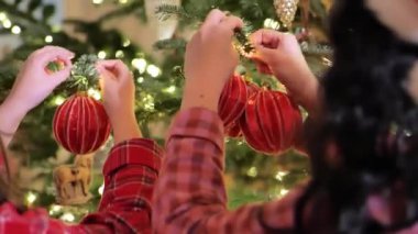 Noel ağacını süslüyordum. Noel ağacı için oyuncaklar. Pijamalı anne ve kız Noel ağacını kırmızı toplarla süsleyin. Eller Noel ağacının dallarına topları yerleştirin.. 
