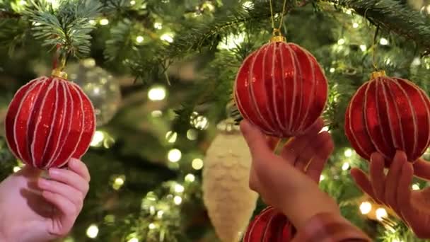 圣诞树上的玩具在母亲和女儿的手中 背景是闪闪发光的圣诞树 装饰圣诞树 4K镜头 — 图库视频影像