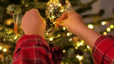 Noel ağacı oyuncağı. Eller Noel ağacının dallarına kırmızı toplar koyuyor. Noel ağacını süslüyor. 4k görüntü