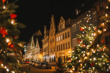 Rothenburg ob der Tauber. Yılbaşı kasabası. Avrupa 'da Noel. Topları ve parlak çelenkleri olan Noel ağacı. Noel akşamı meydanında insanlar yürüyor. Yumuşak odak. 