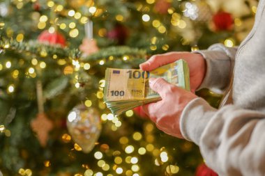 Noel ve Yeni Yıl harcamaları. Bir Noel ağacının arkaplanına, hediyelere ve Noel süslemelerine bağlı olarak, avroya konan para paketi. Kış tatillerinde harcamalar.