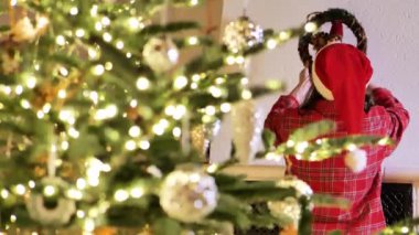 Noel çelengi. Çocuk duvara Noel çelengi asıyor. Noel ve yeni yıl gelenekleri. Kutlama atmosferi. 4k görüntü