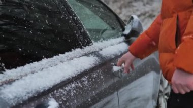 Araba ve kar yağışı. Adam kar yağarken arabanın kapısını açıyor. Yollarda hava kötü. Kış yolu. Kışın karlı havada araba yolculuğu. 4k görüntü