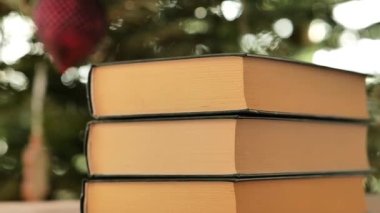 Noel ve Yeni Yıl kitapları. Yeşil kapaklı kitaplar Noel ağacı arka planında. Noel ve kış temaları hakkında kitaplar. 4k görüntü