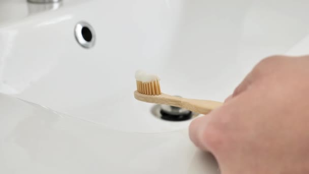 竹制牙刷 手握牙膏 用自来水冲洗 清洁牙齿 手拿着牙刷在明亮的浴室里特写 慢动作 人类卫生概念 4K镜头 — 图库视频影像