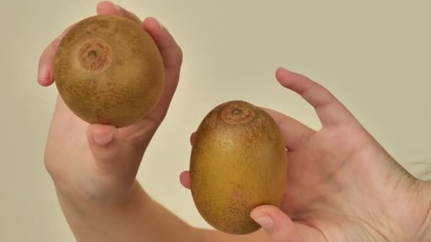 ベージュの背景に子供の手でキウイフルーツ ビタミンC天然源 子供の食糧の新鮮なフルーツ 4K映像について — ストック動画