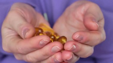 Balık yağı ve kadın sağlığı. Balık yağı kapsülleri dişilerin elinde, yakın plan. Omega üç yağ asidi kadın beslenmesinde. 4k görüntü