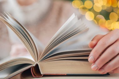 Noel kitapları. Eller süveter içinde Noel çelenkleriyle ilgili bir kitabın sayfalarını çevirin. Noel ve kış temalarıyla ilgili kitaplar. Kış tatilleri boyunca eğitim.