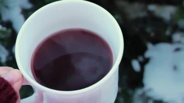 Yılbaşı şarabı. Elindeki beyaz kupada sıcak kırmızı şarap. Soğukta buhar. Noel gelenekleri ve gelenekleri. 4k görüntü