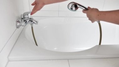 Su tüketimi. Banyo ve duşta su prosedürleri. Duş başlığından sıcak su eline ve küvete dökülüyor. Yıkanmak için su. 4k görüntü