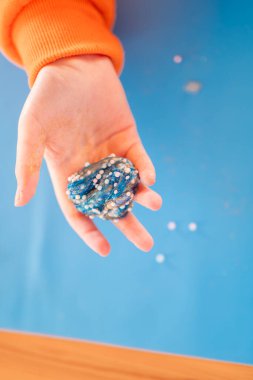 Ahşap bir masada mavi silikon bir hasırın üzerindeki mavi balçık. Yukarıdan bak. Güzel motor beceriler gelişiyor. Ellerde çoğunlukla plastikler.. 