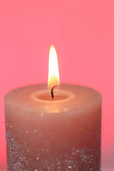 Burning candle close-up.Candle flame.White candle close-up on a pink background.Beautiful background with a candle