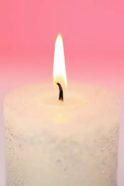 Candle flame.White candle close-up on a pink background.Beautiful background with a candle in pastel colors.