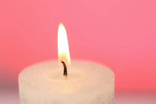 Burning candle close-up.Candle flame on a pink background.Beautiful background with a candle in pastel colors