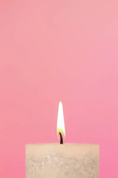 Burning candle .Candle flame.White candle close-up on a pink background.Beautiful background with a candle in pastel colors