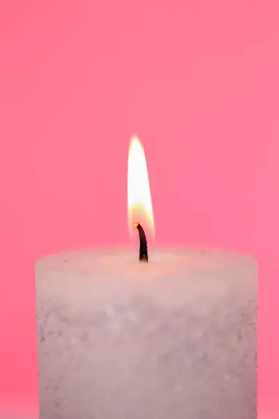 Candle flame close-up on a pink background.Beautiful background with a candle in pastel colors.Burning candle close-up.